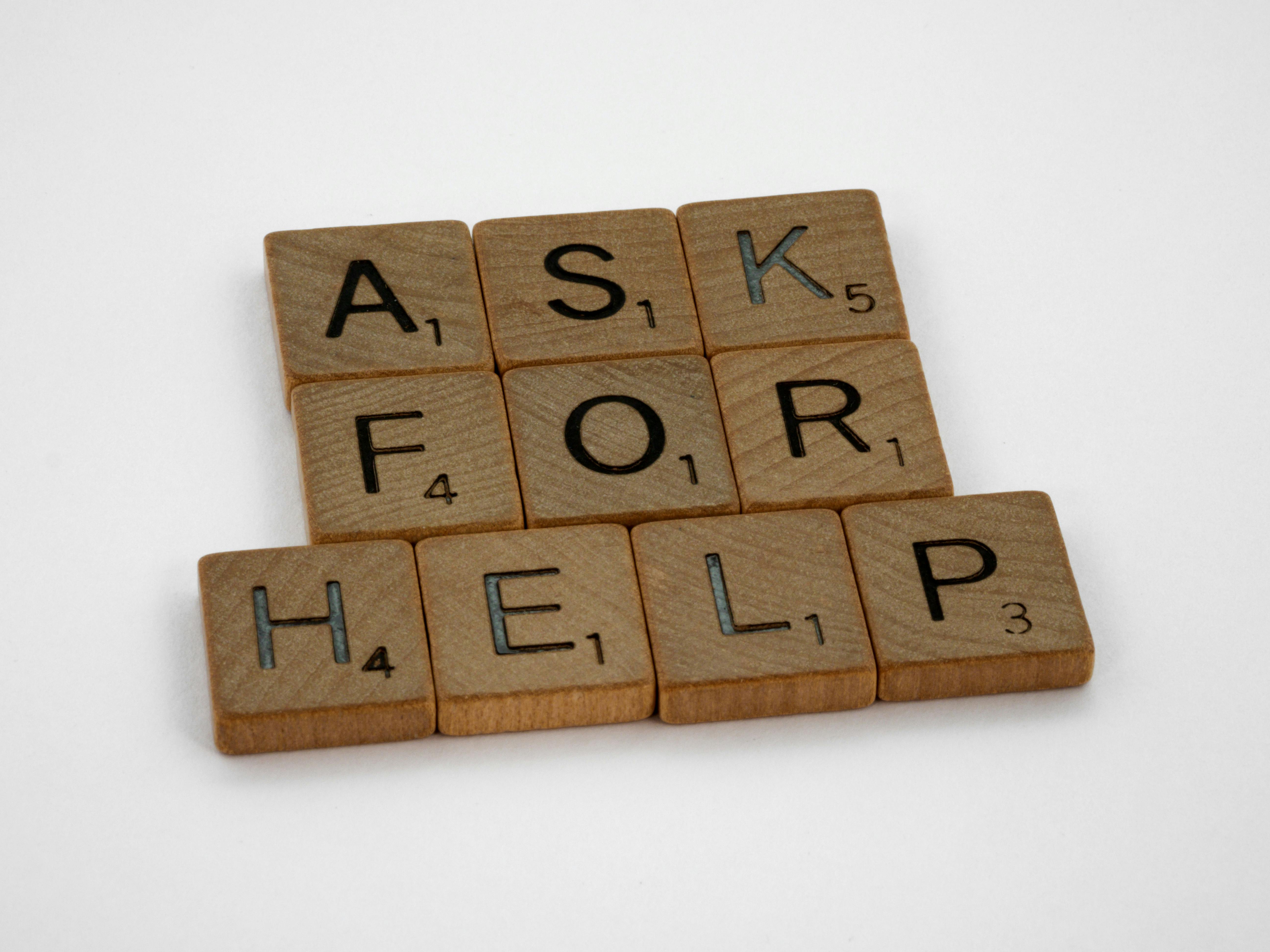 Wooden letter tiles arranged to spell out the phrase "Ask for Help".